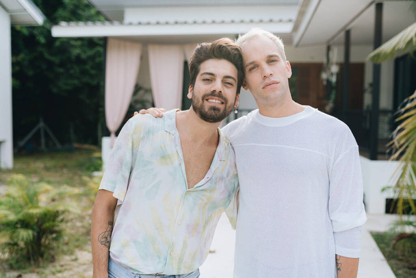 Gay hugging couple standing in front of their house outdoors - Φωτογραφία, εικόνα