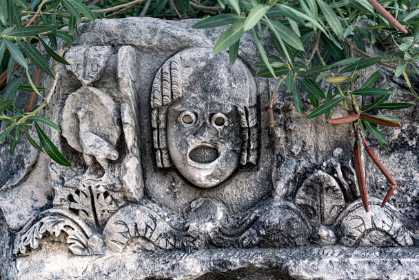 fragment of a wall with stone-cut mask among tropical vegetation in the ruins of the ancient city of Mira, Turkey - Photo, image