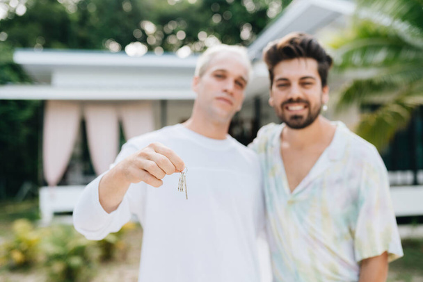 Gay couple standing in front of their house and holding keys of thier new house - Photo, image