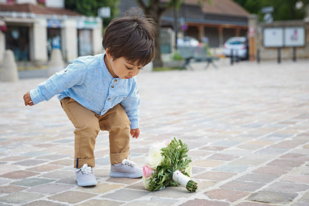 Cute little boy playing outdoor with a bouquet of flowers - Fotografie, Obrázek