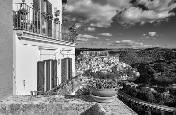 Italy, Sicily, Ragusa Ibla, view of an old house balcony and the baroque town in the background - Foto, Bild