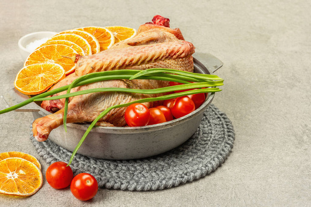 Raw goose with vegetables and spices. Traditional ingredient for preparing festive and healthy food, rustic style. Light stone concrete background, copy space - Photo, Image