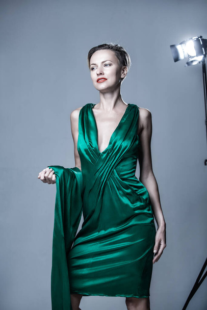 Beautiful woman wearing green silk dress, sunglasses and scarf over grey background - Fotografie, Obrázek