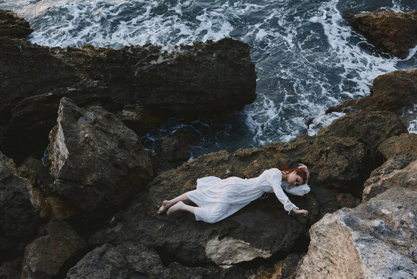 Frau liegt an felsiger Küste mit Rissen an felsiger Oberfläche Naturlandschaft - Foto, Bild