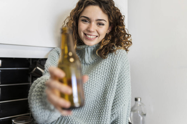pretty curly haired woman having a beer at home - Fotó, kép