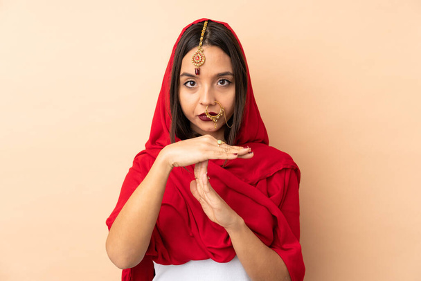 Giovane donna indiana isolata su sfondo beige facendo tempo fuori gesto - Foto, immagini