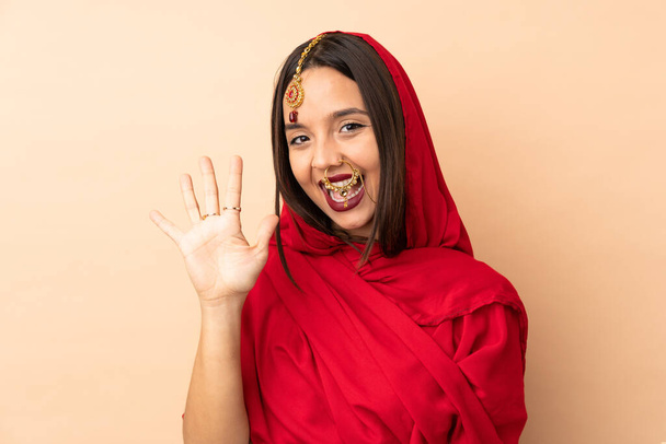 Jovem indiana isolada em fundo bege contando cinco com os dedos - Foto, Imagem