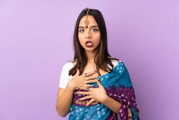 Νεαρή Ινδή γυναίκα απομονωμένη σε μωβ φόντο έκπληκτη και σοκαρισμένη ενώ κοιτούσε δεξιά - Φωτογραφία, εικόνα