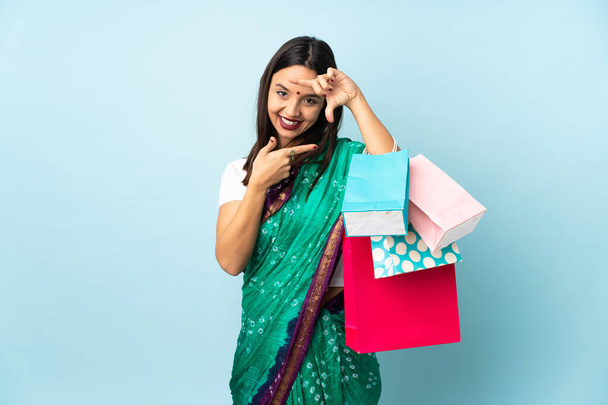 Μια νεαρή Ινδή με σακούλες για ψώνια που εστιάζει το πρόσωπό της. Σύμβολο πλαισίου - Φωτογραφία, εικόνα