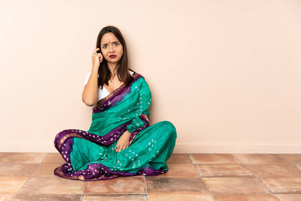 Young Indian woman sitting on the floor thinking an idea - Foto, imagen