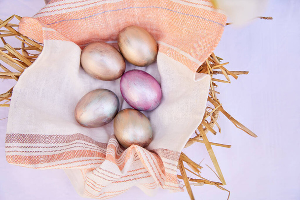 Пасхальні яйця в плетеному кошику з соломи. Перевіряти яйця періоду та апельсина різнокольоровими. Вид зверху
. - Фото, зображення