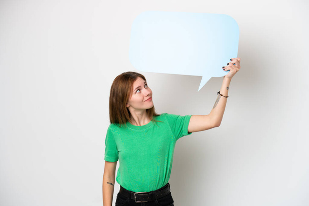 Молода англійська жінка, ізольована на білому фоні, тримає порожню мову бульбашку - Фото, зображення