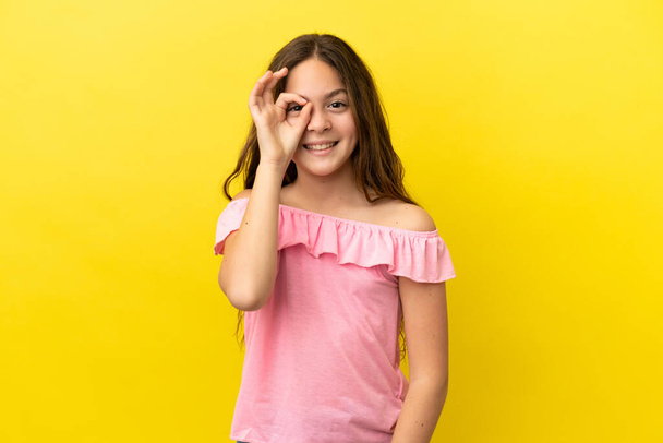 Little caucasian girl isolated on yellow background showing ok sign with fingers - Photo, image