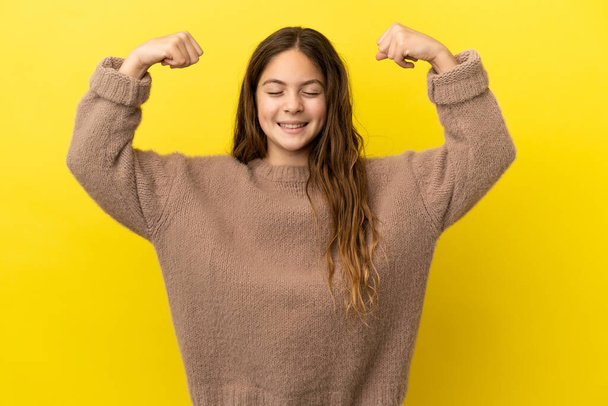 Little caucasian girl isolated on yellow background doing strong gesture - Foto, immagini