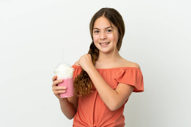 Little caucasian girl with strawberry milkshake isolated on white background celebrating a victory - Fotó, kép
