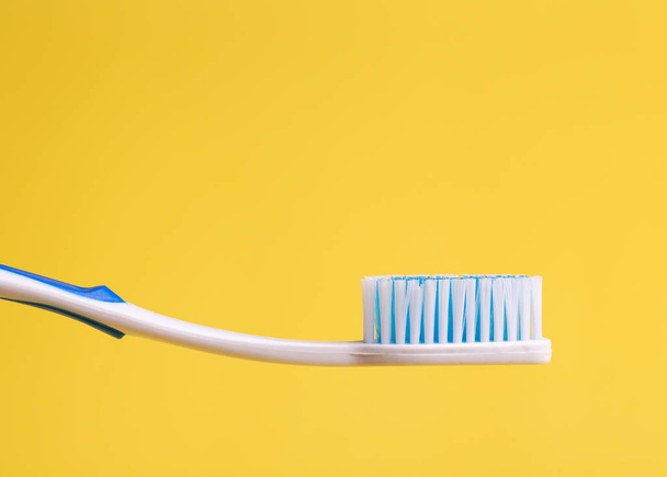 Clean toothbrush on a yellow background side view. - Fotó, kép