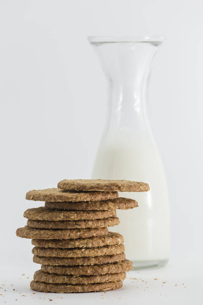 glass bottle full of milk and a bunch of cookies in front, all isolated on white background - Fotoğraf, Görsel
