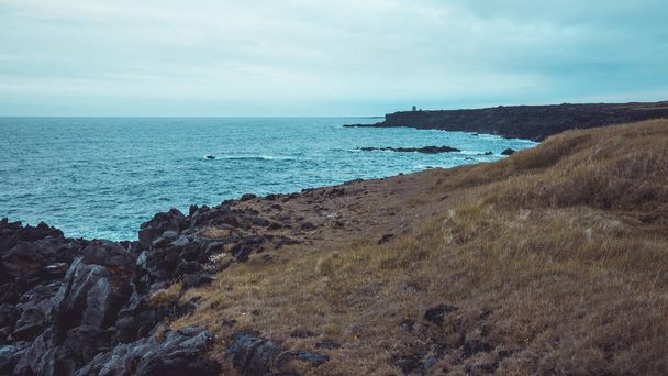 Basalt rock formations and cliffs on Hellnar region of Iceland on a cloudy day in summer. Majestic views over cliffs on Iceland - 写真・画像