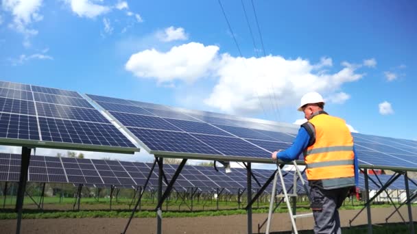 Man climbs a stepladder to solar panels. Male engineer working at a solar power plant - Video
