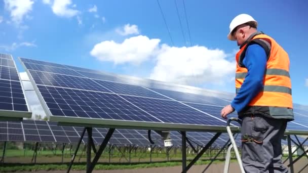 Man assembles solar panels at a power plant. process of fixing solar panels on a metal base - Záběry, video
