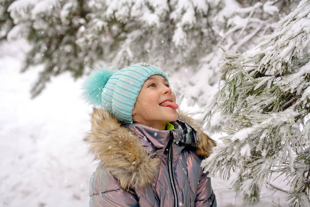 A girl in warm winter overalls on a walk in the winter forest: active games, playing snowballs and other activities - Foto, Imagen