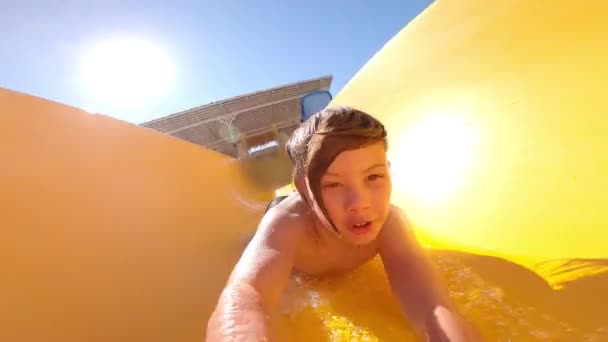 Boy go down the yellow water slide. Children rejoice going down the water slide. Fun on the waterslide. - Footage, Video