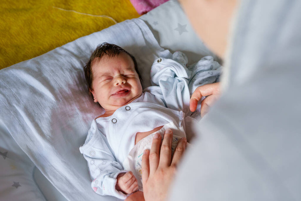 Top view valkoihoisesta vauvasta unelias haukottelu samalla kun vaihdetaan vaippoja ja vaatteita sängyssä kotona vanhemmuus lapsuuden uusi elämä ja kasvaa käsite - Valokuva, kuva