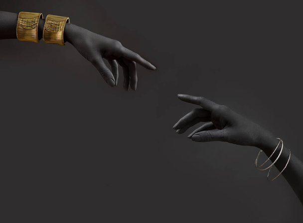 Black woman's hands with gold jewelry. Oriental Bracelets on a black painted hand. Gold and silver Jewelry and luxury accessories on black background closeup. High Fashion art concep - Photo, Image
