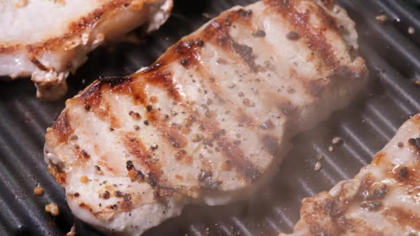 Close up view on Meat with golden crust is fried on an electric grill close up. 4K resolution video. Pork steaks close up are fried and smoked on the grill - Footage, Video
