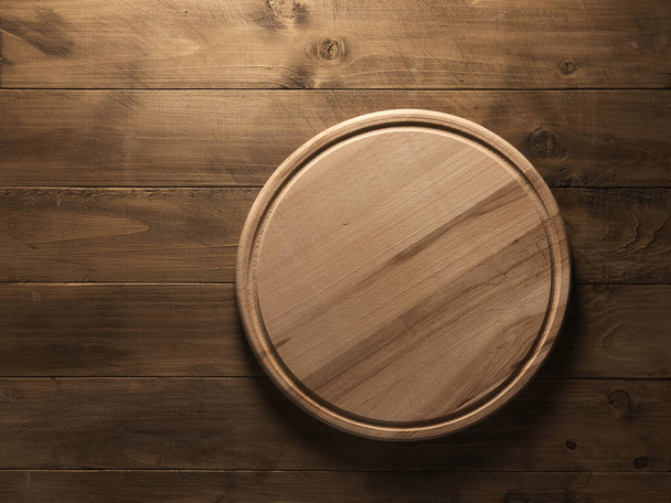 Round kitchen board on wooden table - Foto, afbeelding