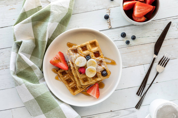 Top down view of a plate of whole grain waffles topped with sliced fruit. - Foto, Imagem