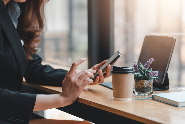 Εικόνα μιας επιχειρηματία που κάθεται με το χέρι χρησιμοποιώντας smartphone σε μια καφετέρια. - Φωτογραφία, εικόνα