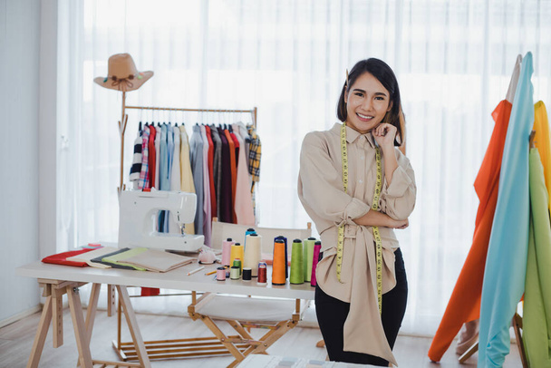 Πορτρέτο Ασίας σχεδιαστής ρούχα γυναίκα με σταυρό χέρια κάποιου στο γραφείο με επιτυχία των επιχειρήσεων. Σχέδιο σχεδιαστών εκκίνησης. Οι σχεδιαστές ρούχων δουλεύουν στο στούντιο.. - Φωτογραφία, εικόνα