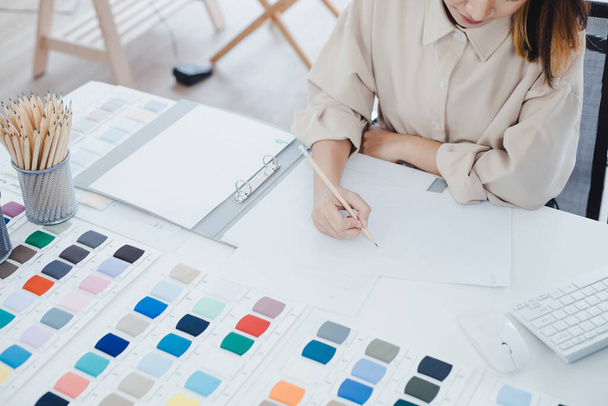 Professionelle Modedesignerin zeichnet ein neues Kleidungsmodell mit Bleistift auf dem Papier für Kunden mit Bestellung im Atelier. - Foto, Bild