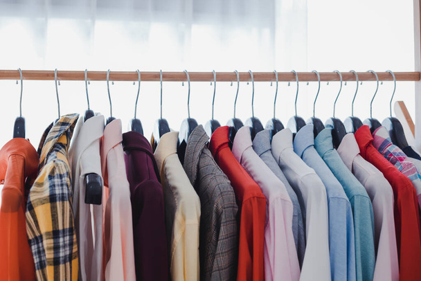 Variety and modern fashion clothes, orderly hanging on the clothesline. Clothes hang on shelf in a designer clothes store. Row of clothes hanging on rack. Fashion trend concept. - Foto, immagini