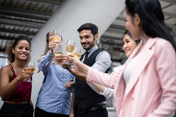 Biznesmeni piją kieliszki i piją wino, by uczcić sukces pracy. Grupa ludzi biznesu świętują pijąc wino. - Zdjęcie, obraz