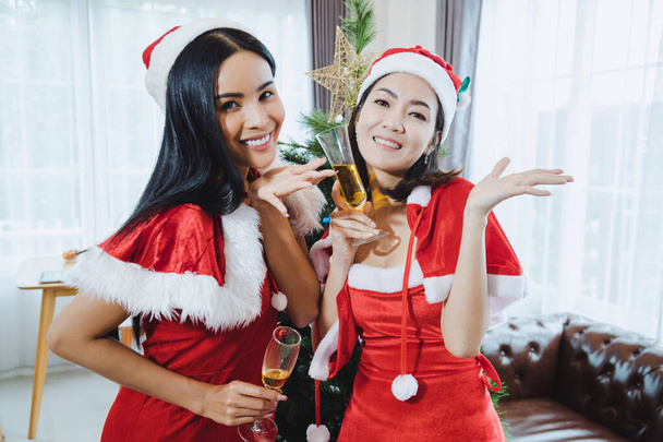 Two sexy santa women celebrate Christmas party together with drink wine in the home. - Foto, imagen