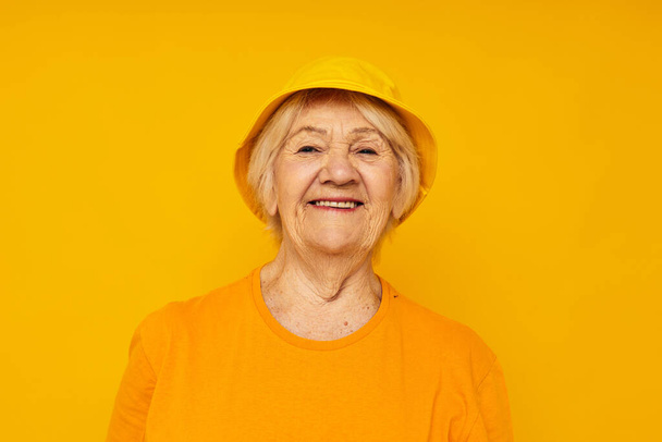 Photo of retired old lady happy lifestyle in a yellow headdress yellow background - Zdjęcie, obraz