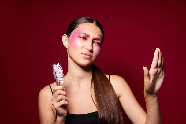 Beauty fashion female pink face makeup posing attractive look with a comb pink background unaltered - Φωτογραφία, εικόνα