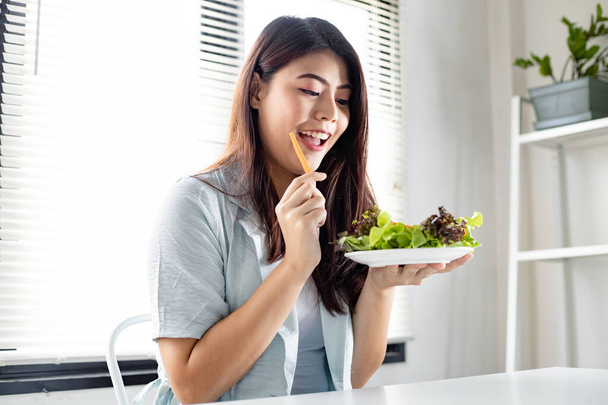 Concepto de dieta por comer ensalada saludable. Mujer joven sosteniendo plato vegetal para una dieta saludable con sonrisa en la atención médica. - Foto, Imagen