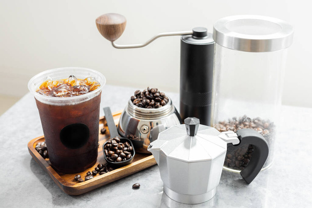 Iced black coffee in plastic cup with black logo sticker on wooden tray. Americano from moka pot style italian. - Foto, Imagem