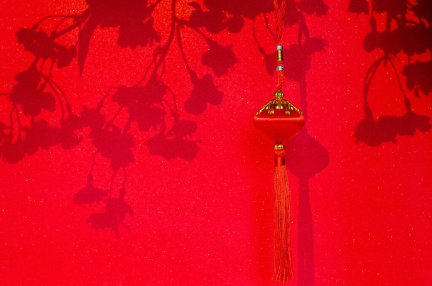 Hanging pendant for Chinese new year ornament with shadow of peach blossom flowers on red glitter paper background. - Foto, Bild