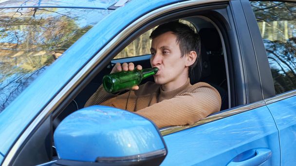Şoför, işten sonra araba kulübesinde şişeden alkol içiyor. - Fotoğraf, Görsel