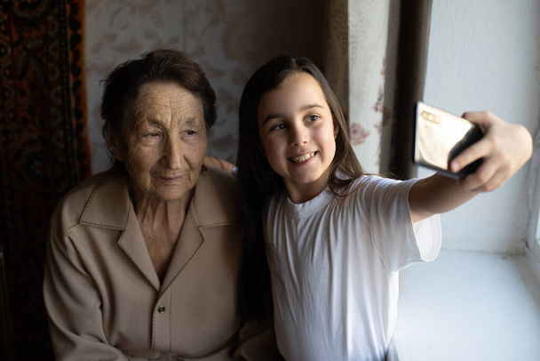 hyvin vanha iso-isoäiti ja tyttärentytär älypuhelimella verkossa - Valokuva, kuva