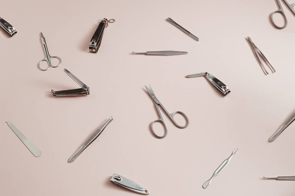Pattern made of scissors, nail clippers, tweezers, files on a coral background - 写真・画像