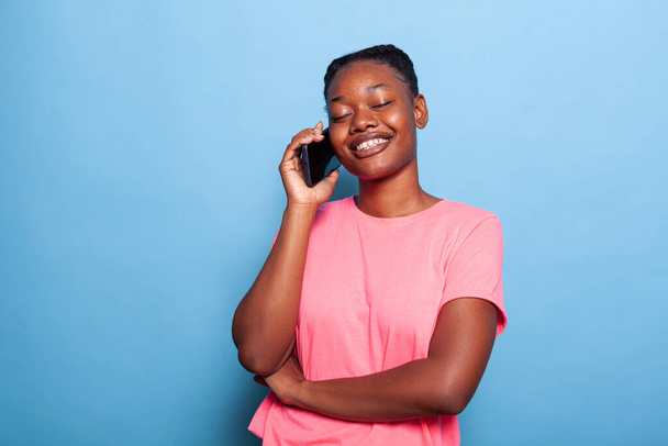 Портрет улыбающегося африканского подростка, разговаривающего по телефону с другом - Фото, изображение
