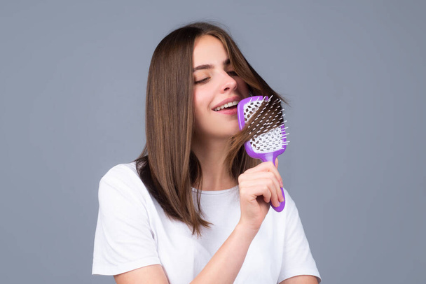 Portrait of smiling brunette hair lady combing hair with hairbrush comb, isolated. Young beautiful woman brush long healthy brunette hair, classic hairstyle, restoration mask, haircare concept. - Foto, Imagen