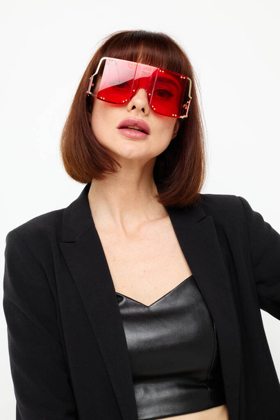 beautiful woman in a black jacket red nail polish fashion glasses light background - Фото, зображення
