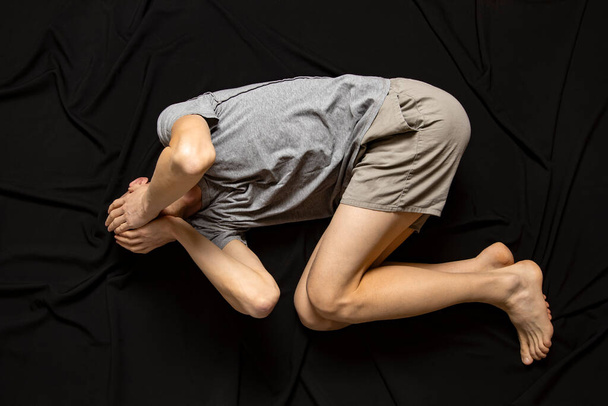 A depressed man on a black background is holding his head. Mental health. - Fotoğraf, Görsel