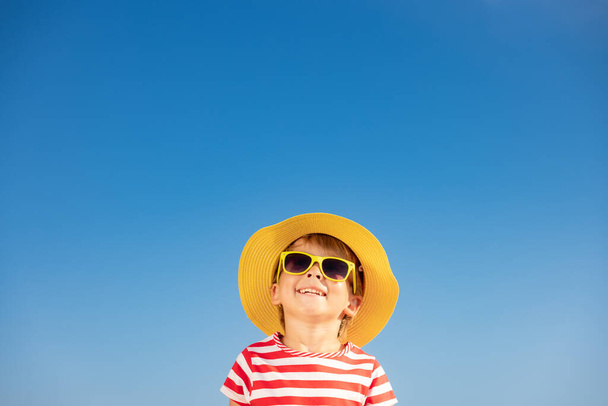 Happy child having fun outdoor against blue sky background. Portrait of smiling kid on summer vacation. Freedom and travel concept - Foto, imagen